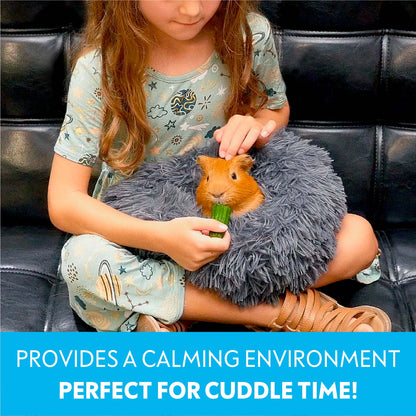 A young child holding a guinea pig inside a dark grey Paw Inspired Furr-O bed on her lap while feeding it a cucumber slice.