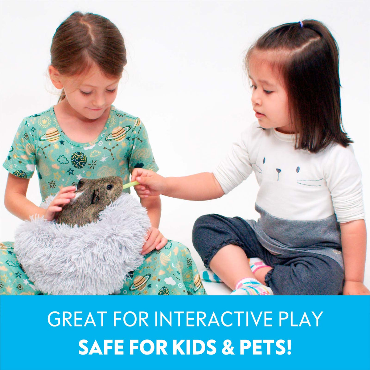 Two young girls playing interactively with a guinea pig resting in a light grey Paw Inspired Furr-O plush bed.