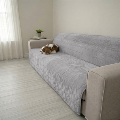 A small brown and white dog resting on a Gray Paw Inspired Anti-Slip Furniture Protector. The quilted, waterproof cover is shown protecting a modern fabric sofa from pet hair and messes.