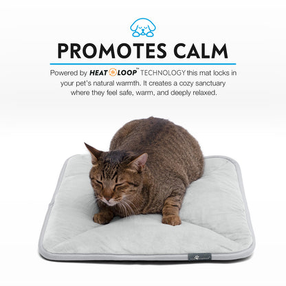 A brown tabby cat relaxing snugly on a grey Paw Inspired self-heating pet mat.