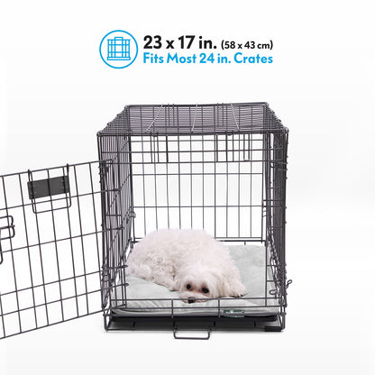 A white dog resting on a grey Paw Inspired self-heating crate liner measuring 23 by 17 inches inside a 24-inch wire crate.