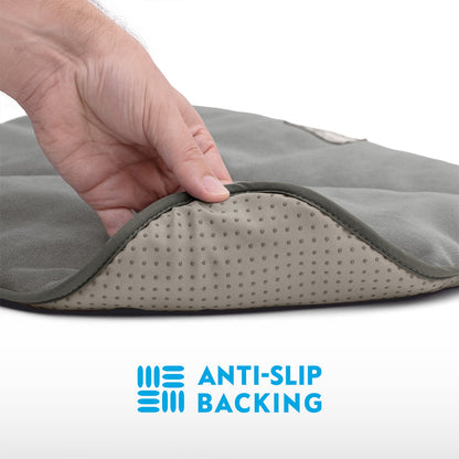 A close-up view of a hand lifting the corner of a grey Paw Inspired self-heating pet mat to show the anti-slip dot backing.
