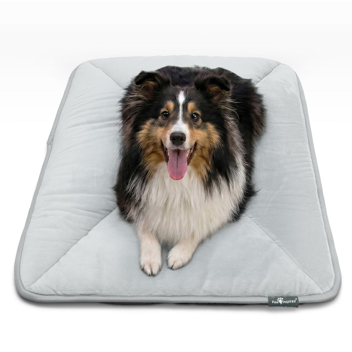 A Shetland Sheepdog resting on a gray Paw Inspired self-heating crate mat.