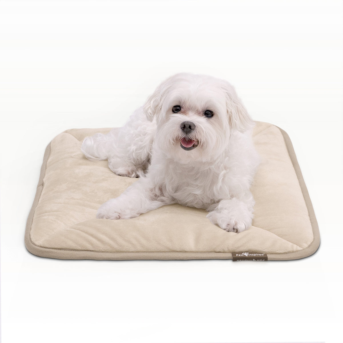 A small white dog resting on a tan Paw Inspired self-heating pet mat.