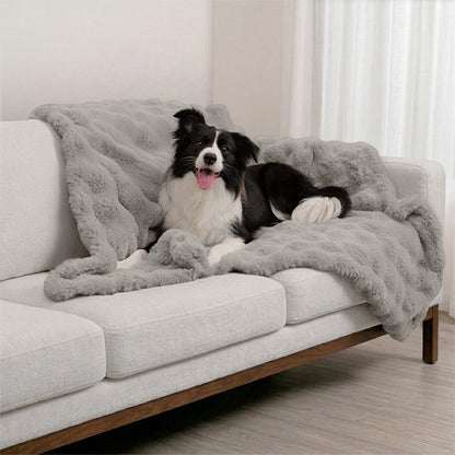 A Border Collie dog laying on a Paw Inspired large grey waterproof faux fur blanket (50x60 in) used as a protective cover for a light-colored sofa.