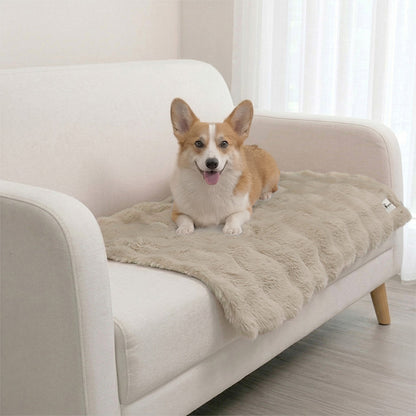 A Corgi relaxing on a Paw Inspired tan waterproof pet blanket, protecting a white fabric sofa from pet hair and accidents.