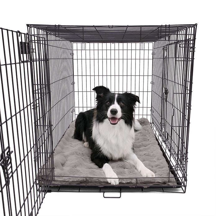 A Border Collie lying comfortably on a Paw Inspired large grey waterproof faux fur blanket (50x60 in) used as a protective and cozy dog crate mat.